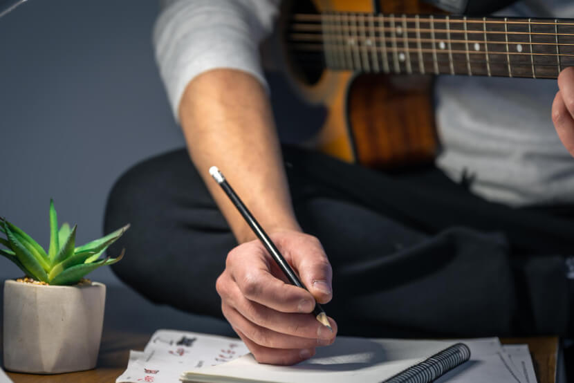 man transcribes music by ear with his guitar