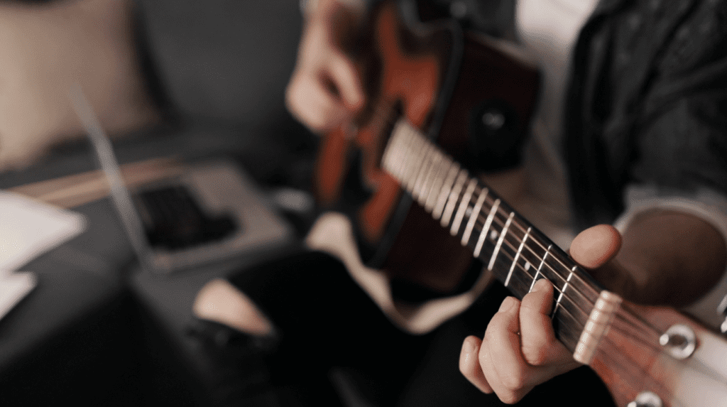 Person playing guitar trying to transcribe his playing by ear.